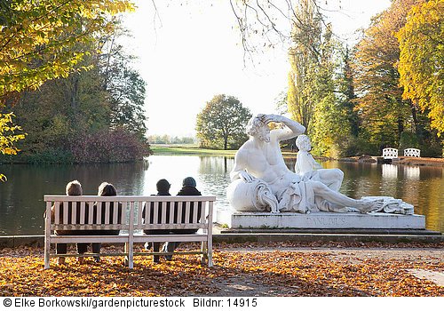 Besucher auf Bank am Seeufer und Statue  Vater Donau darstellend